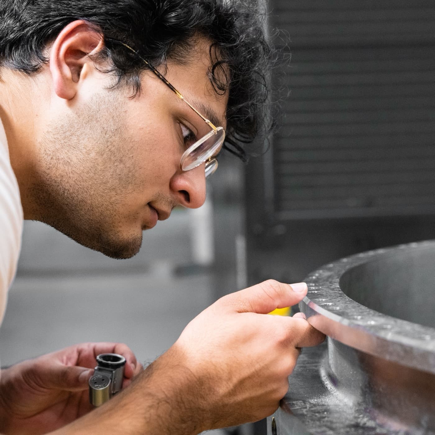 An intern measures the cut of a machined engine casing