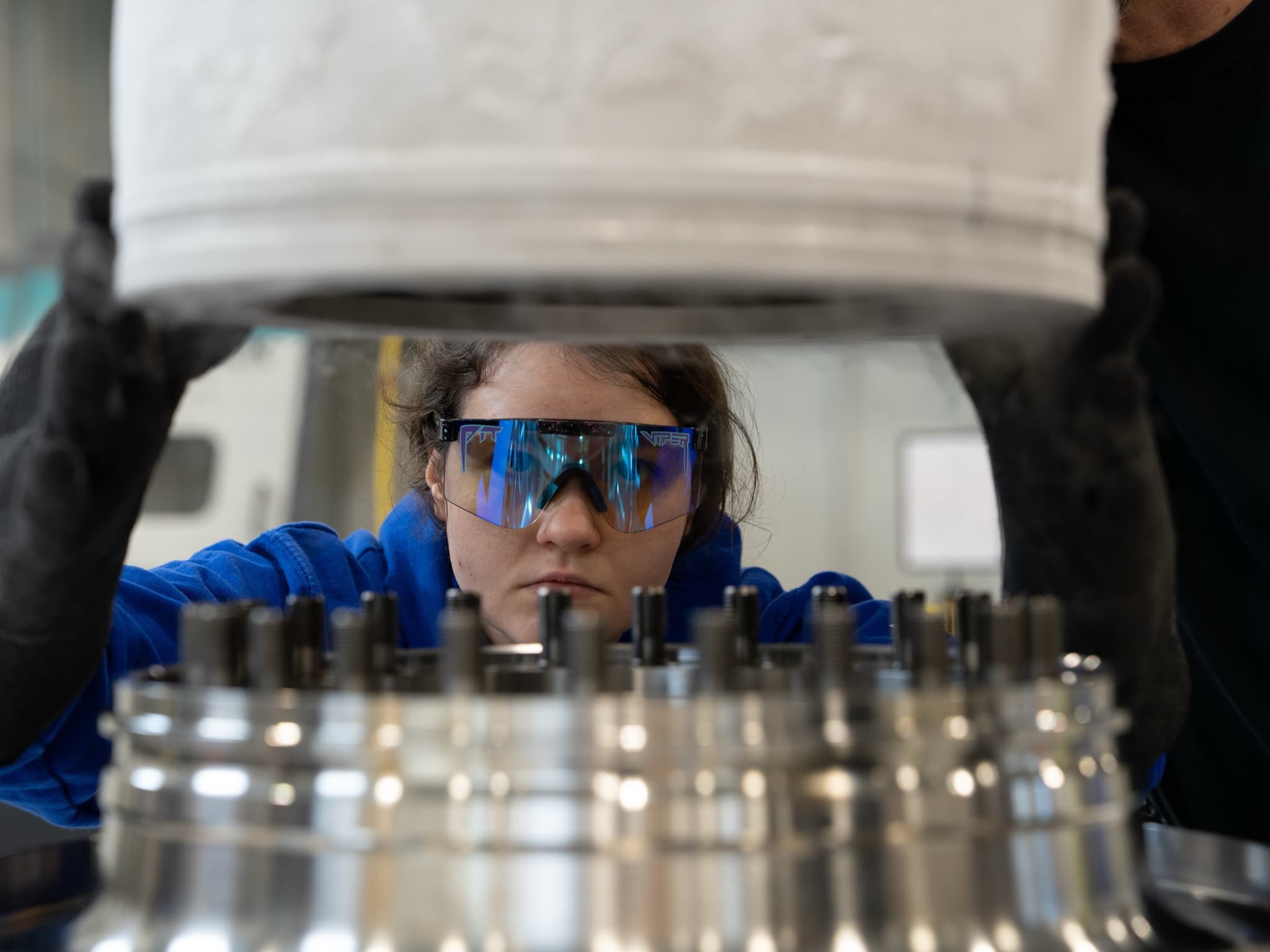 A new-grad engineer lowers a component onto a machined turbomachinery hub