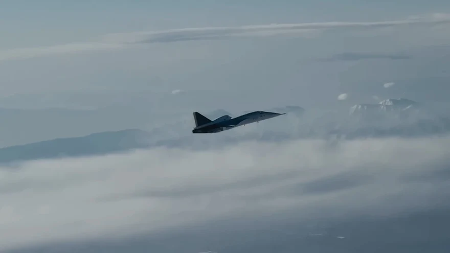 XB-1 in flight, far off above a layer of cloud